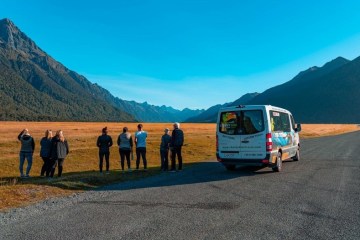 a group of people standing in front of a mountain road