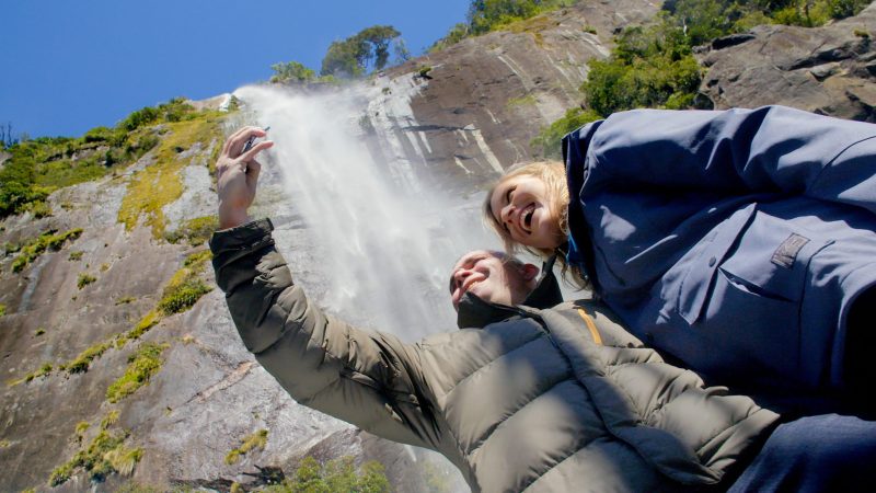 Get up close and personal with towering waterfalls people taking a photo