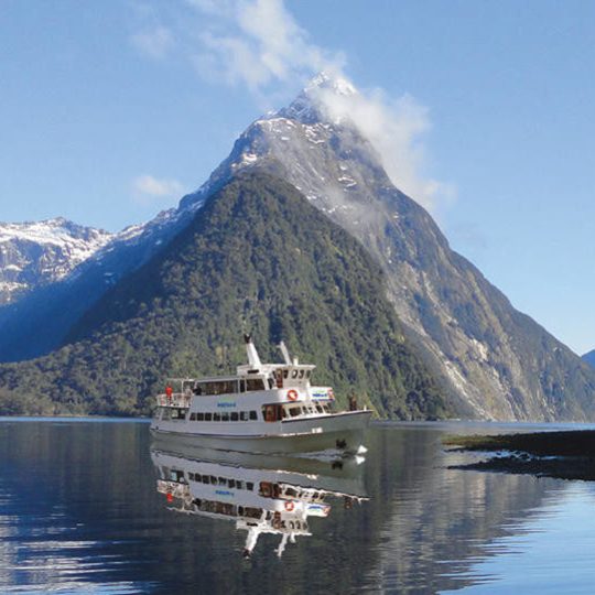 a small boat in a body of water with Milford Sound in the background