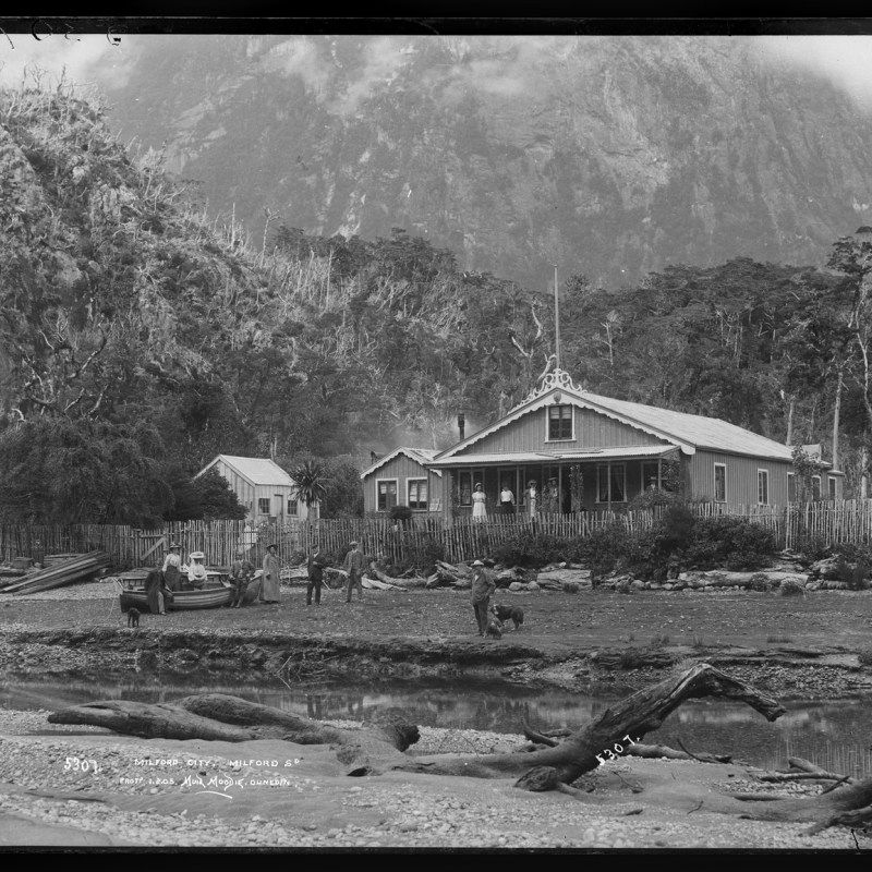 a vintage photo of an old building with a mountain in the background