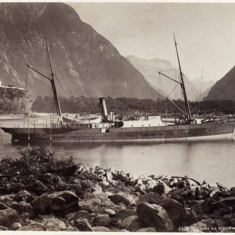 a boat floating on a rocky shore next to a body of water